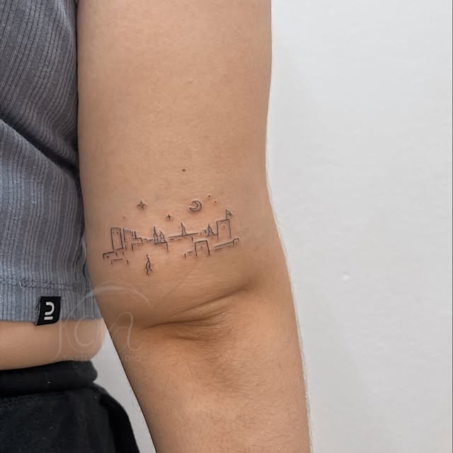Tatuaje fineline de skyline con luna y estrellas