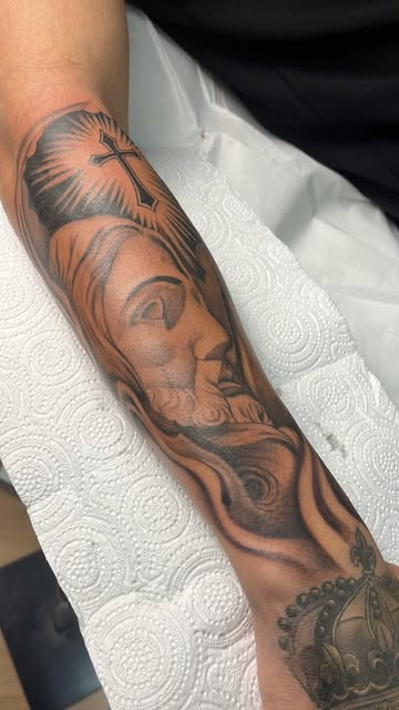 Tatuaje realista de rostro religioso en el antebrazo