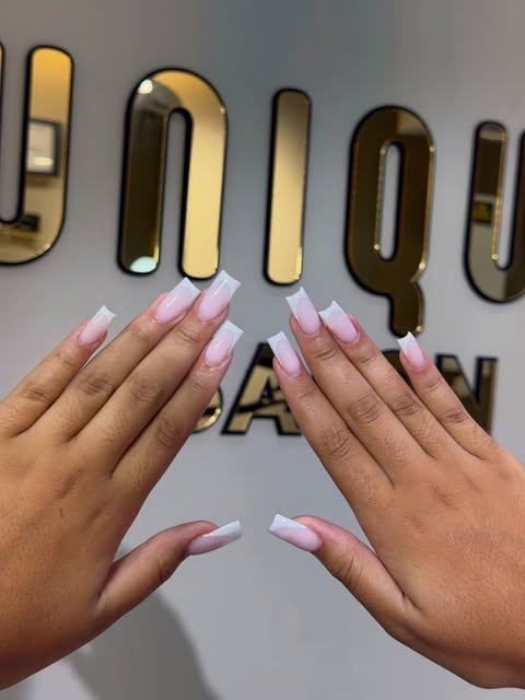 Manicura francesa rosa frente al rótulo dorado de UNIQUE